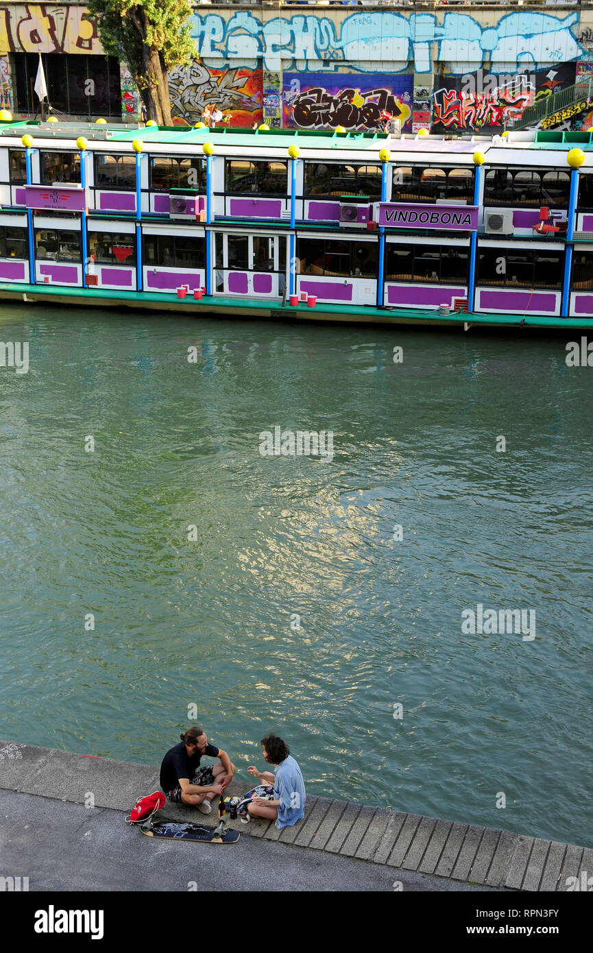 A couple chilling along the Danube canal (Donaukanal) in the summer, Vienna, Austria Stock Photo