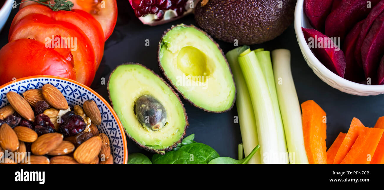 Healthy food selection top view with avocados, raw veggies, green leaves spinach, herbs and ingredients, mix of nuts, clean eating, healthy vegan food Stock Photo