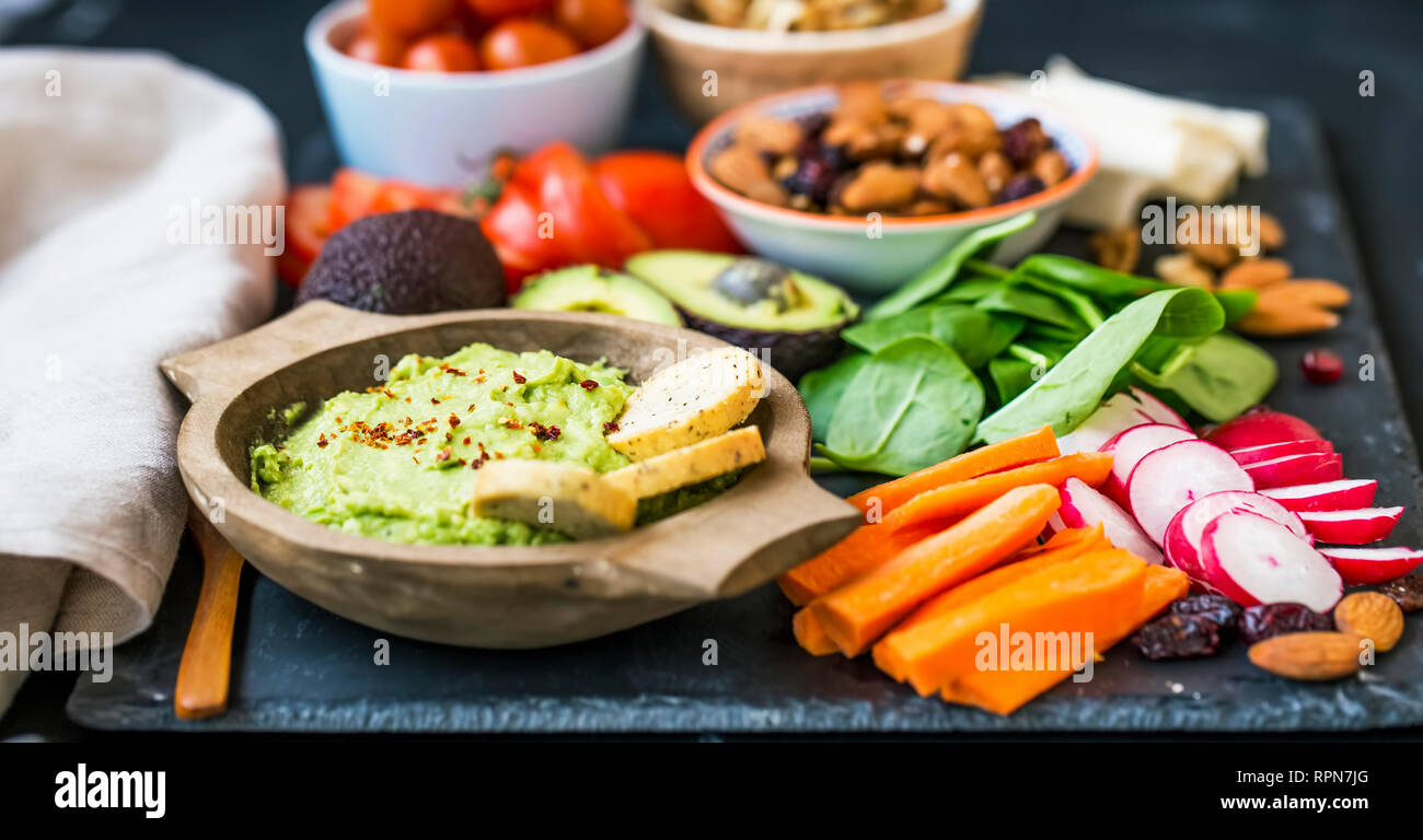 Healthy food selection with guacamole , raw veggies, green leaves spinach, herbs and ingredients, mix of nuts, clean eating, healthy vegan food concep Stock Photo