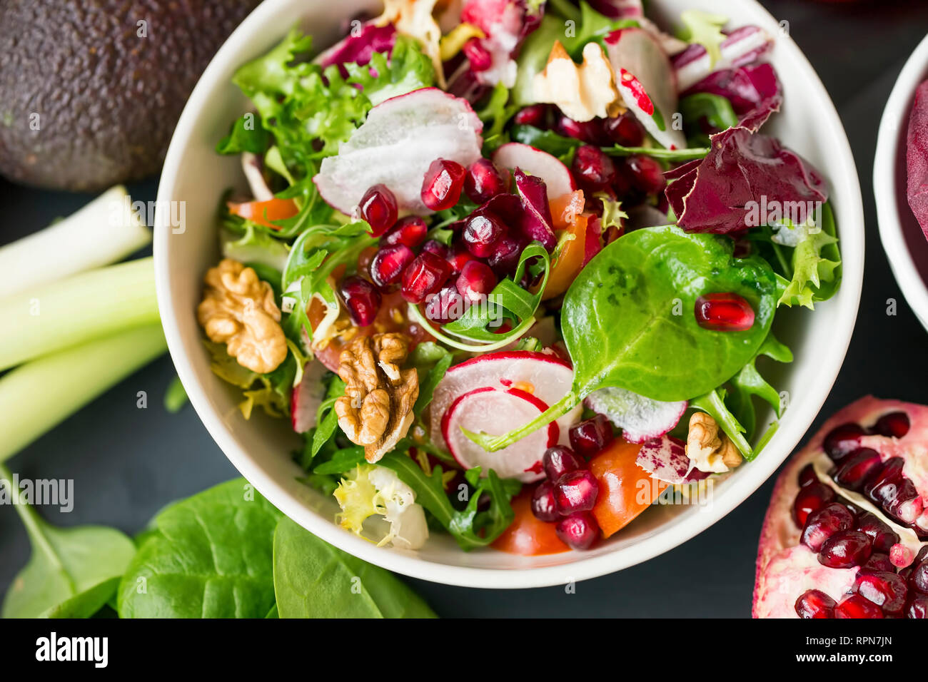 Healthy vegan salad mix in a bowl with nuts, arugula, spinach, radish, tomatoes, pomegranate seeds, top view, healthy clean eating vegan food diet con Stock Photo