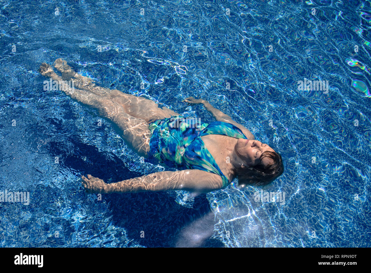 Senior woman floating in the swimming pool. Stock Photo