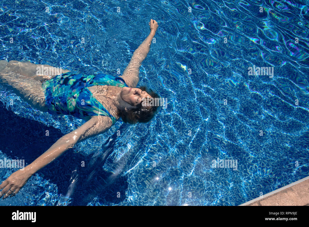 Senior woman floating in the swimming pool. Stock Photo
