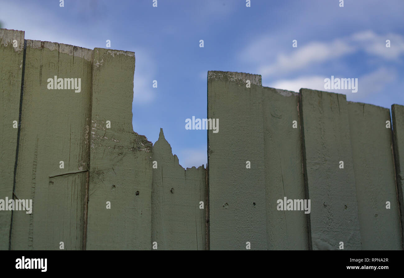 Close up view of broken wooden fence with blue sky background Stock Photo