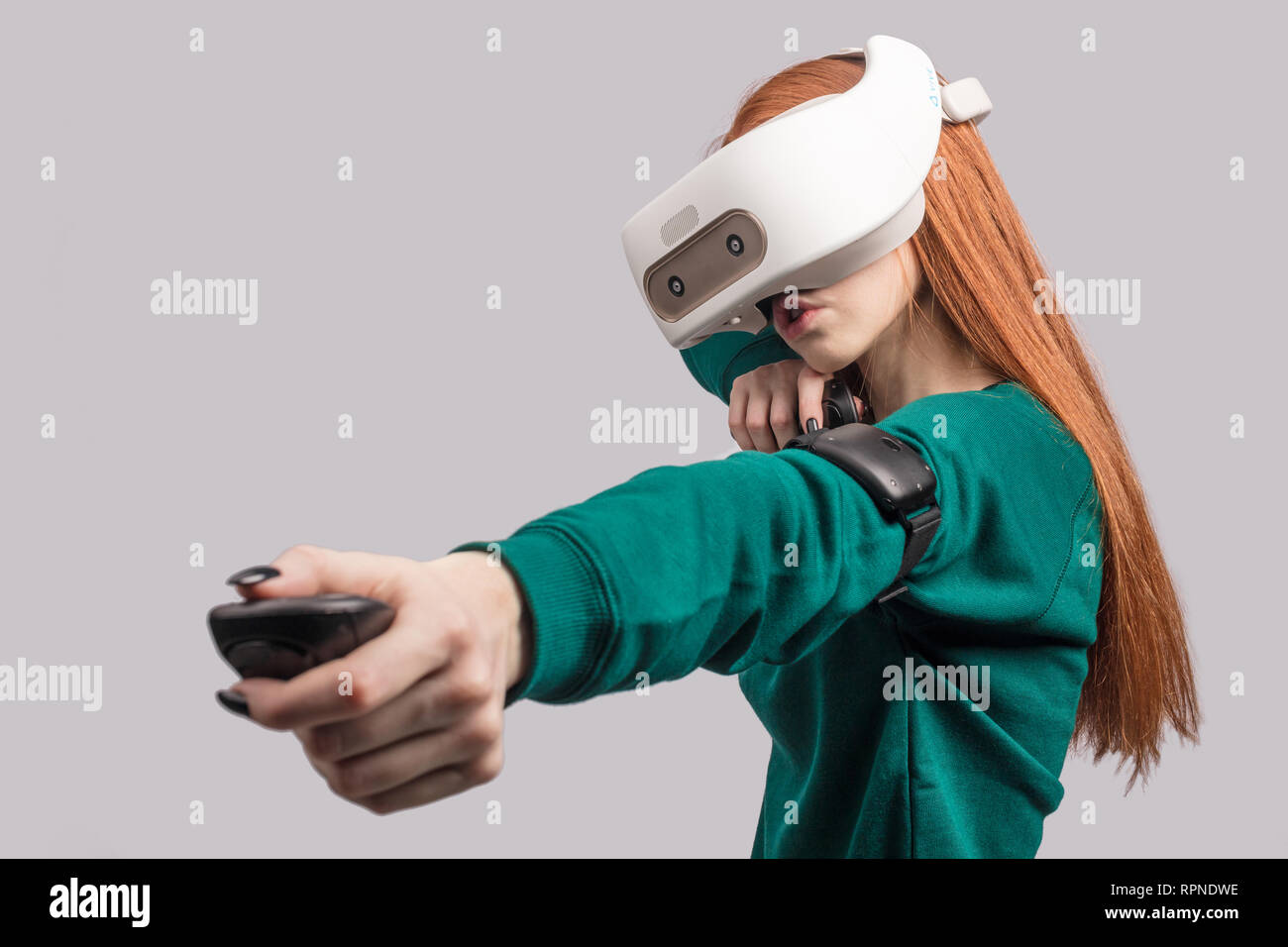 Active beautiful female player with long red hair , being excited watching virtual  reality play with vr glasses on head, acting like an archer, aiming Stock  Photo - Alamy