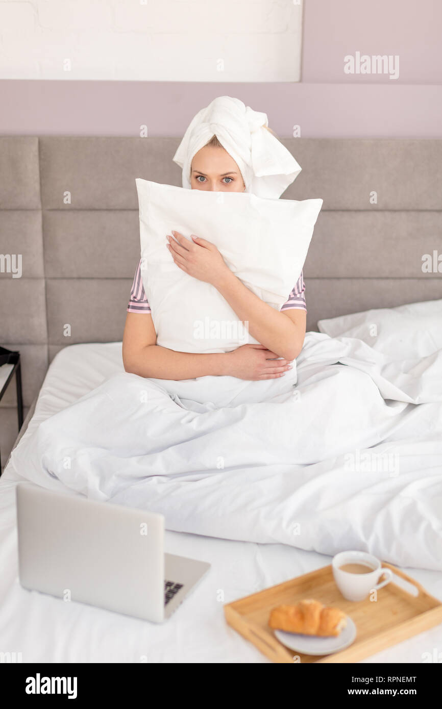 frightened woman embracing the pillow as she is afraid of somebody