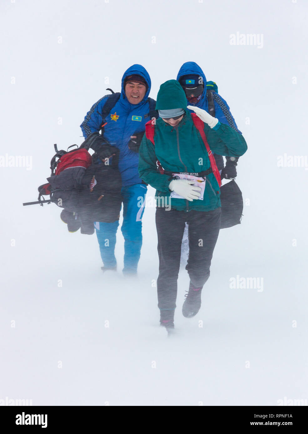 ALMATY KAZAKHSTAN - FEBRUARY 03 2019: Unidentified people walk through a snowstorm during the AlpineRais competition in the mountains during the Stock Photo