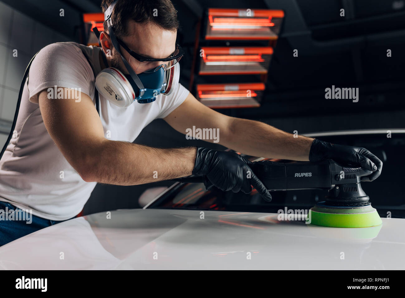 mechanic in a respirator applies the polish. close up photo Stock Photo
