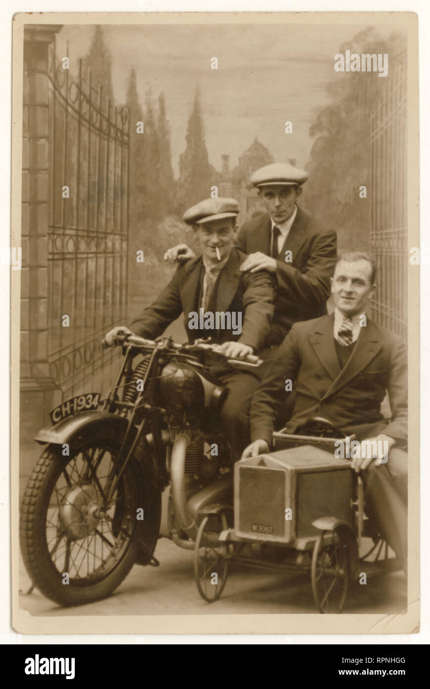 Original 1930's studio portrait postcard of happy men wearing suits and flat caps, posing on motorbike prop, enjoying their annual holiday or leave, dated 20 October 1934, Blackpool, Lancashire, U.K. Stock Photo