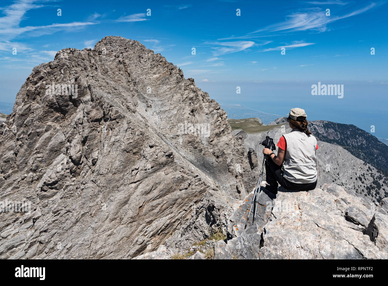 A woman hiker admires the view of Mytikas, the summit of Mount Olympus , on August 5, 2017 in Greece Stock Photo
