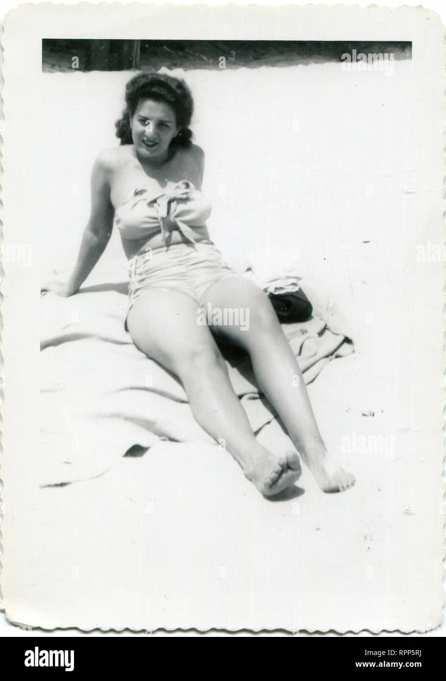 America, United States, 1940s. A young woman in a beautiful bathing suit sunbathes on the beach Stock Photo
