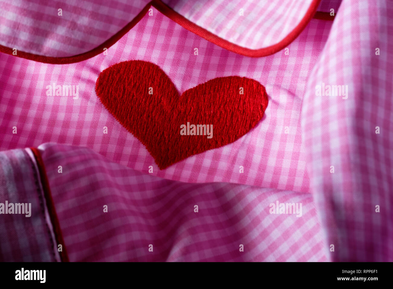 Pink and white checked gingham fabric with red heart. Cotton nightwear. Stock Photo