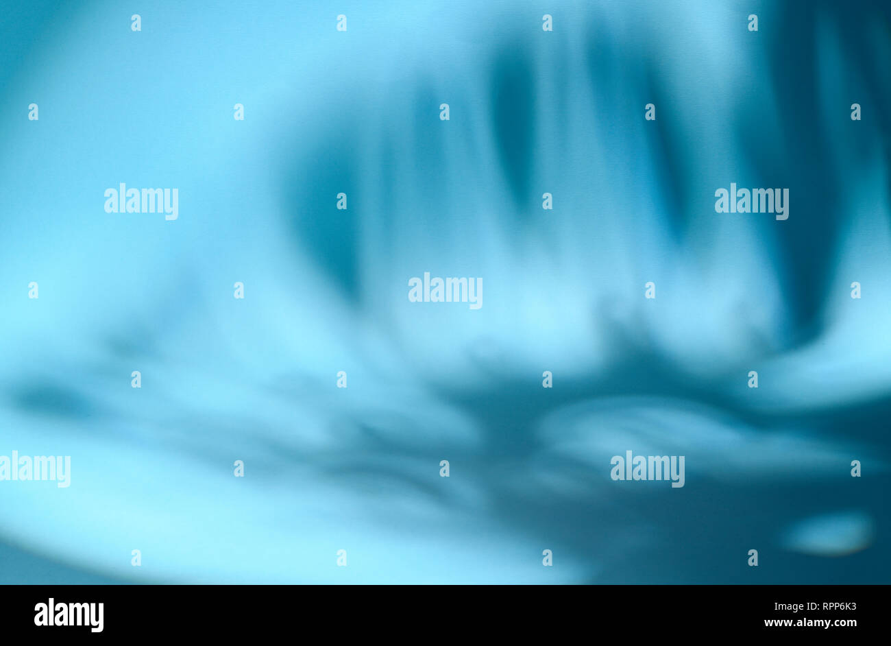 Shaded area in the shape of a tropical leaf. Dappled light. Blue background. Stock Photo