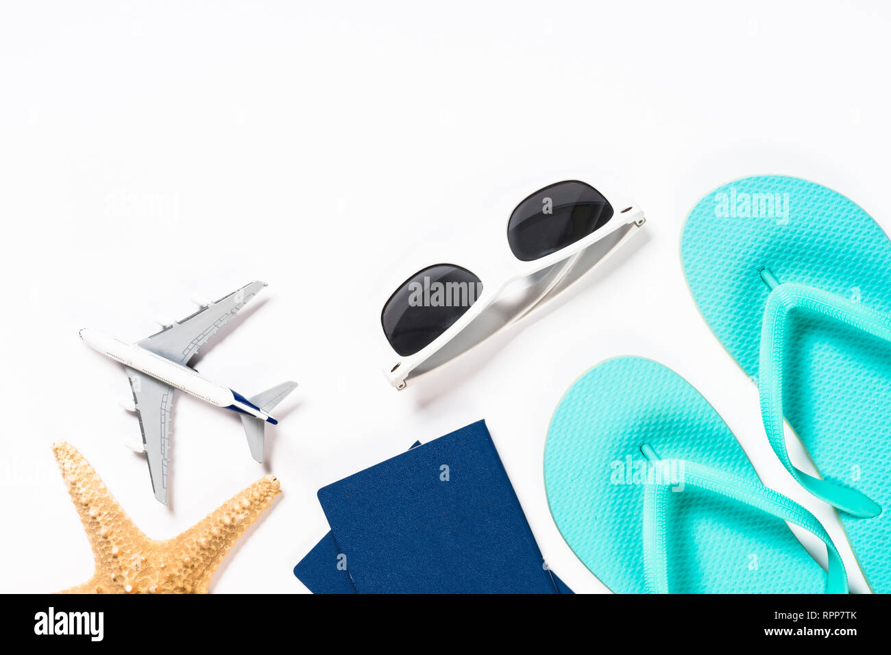 Blue flip flops, sunglasses, passport, plane and starfish on white background. Stock Photo