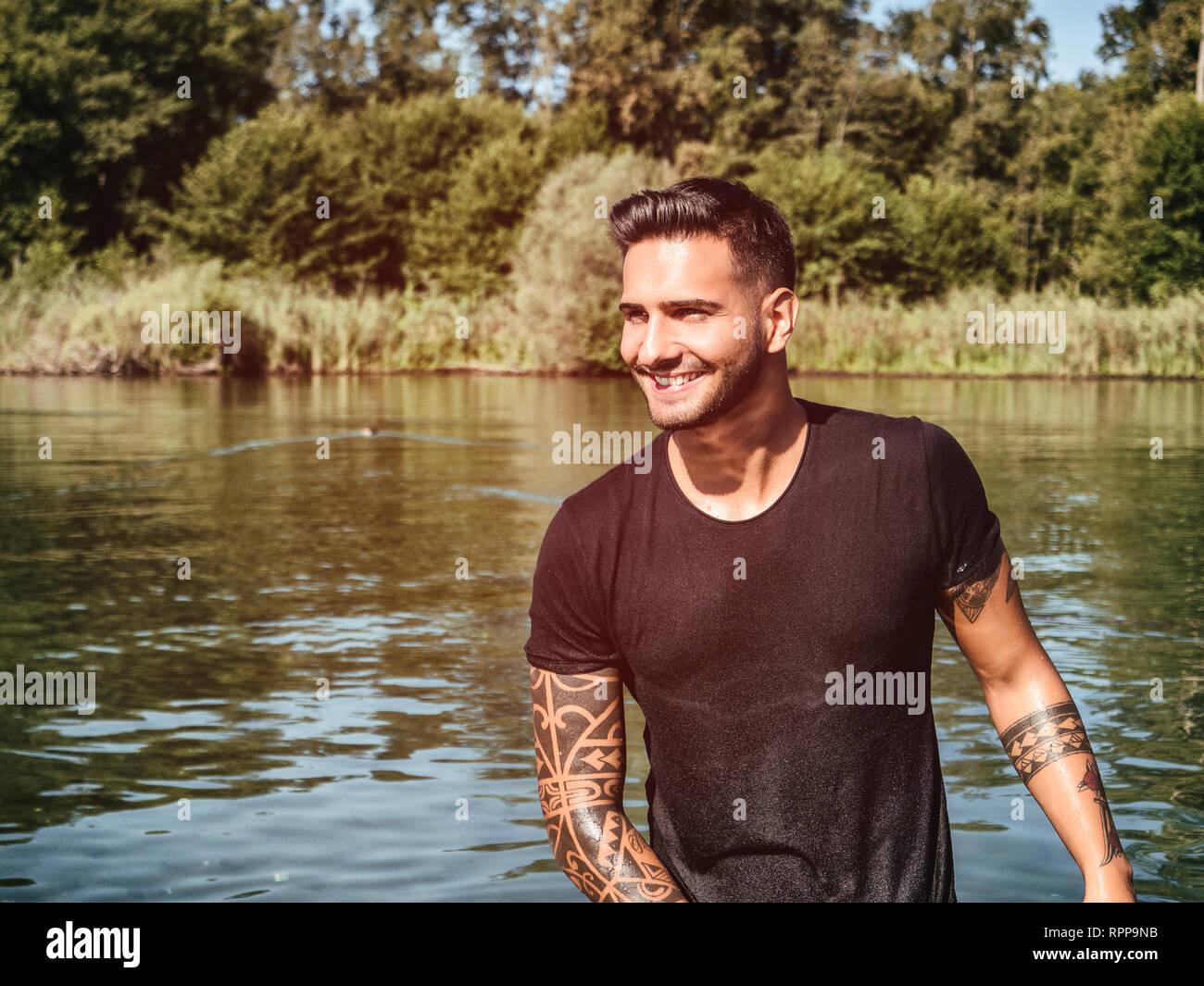 Handsome man in pond with wet t-shirt Stock Photo - Alamy