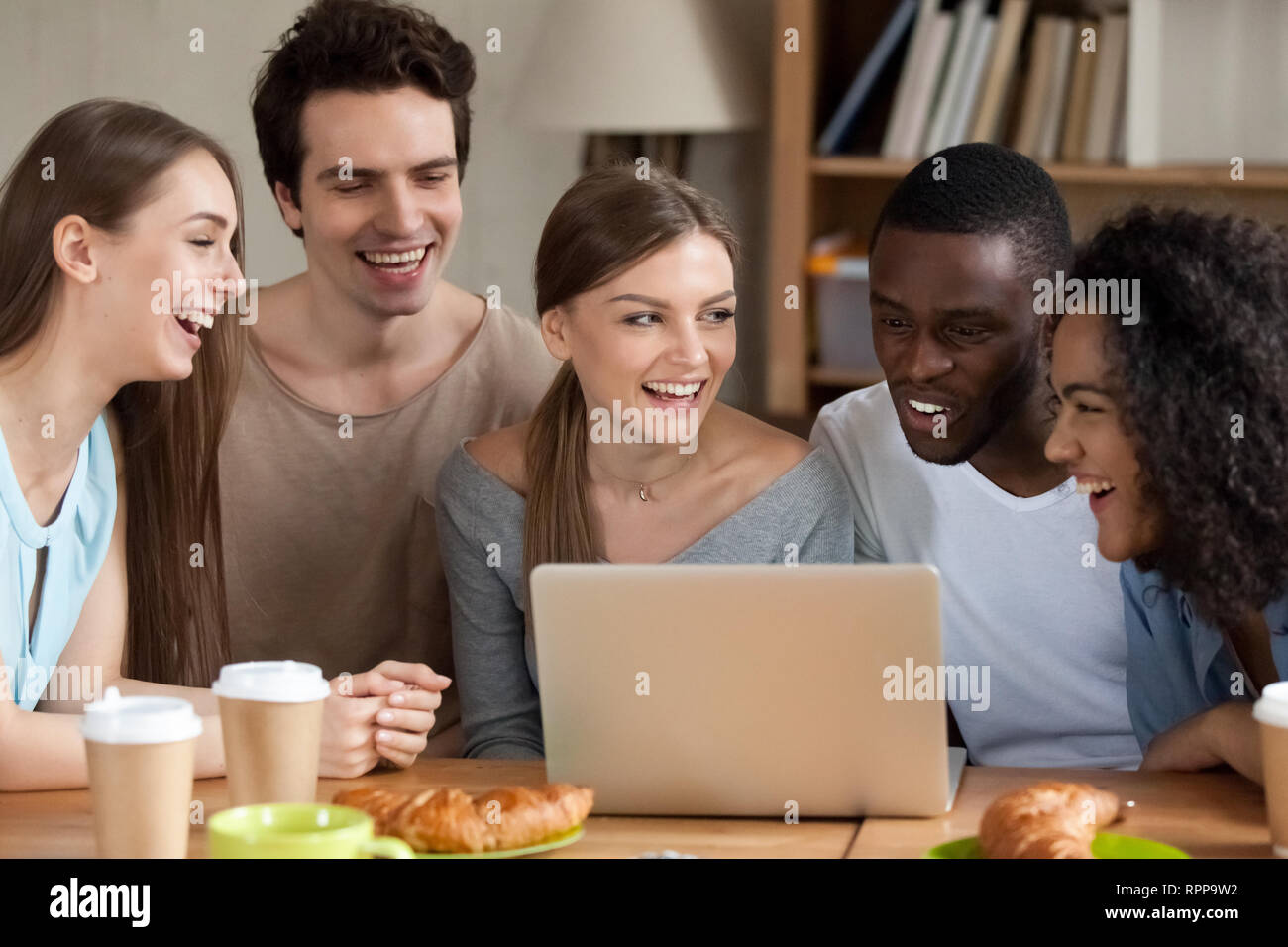 Smiling multiracial people using laptop together, having fun Stock Photo