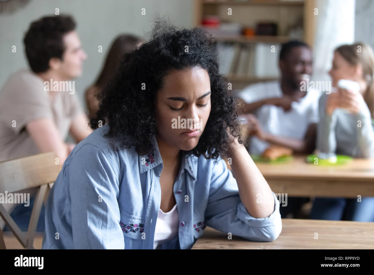 Upset mixed race woman offended by friends, feeling unhappy Stock Photo