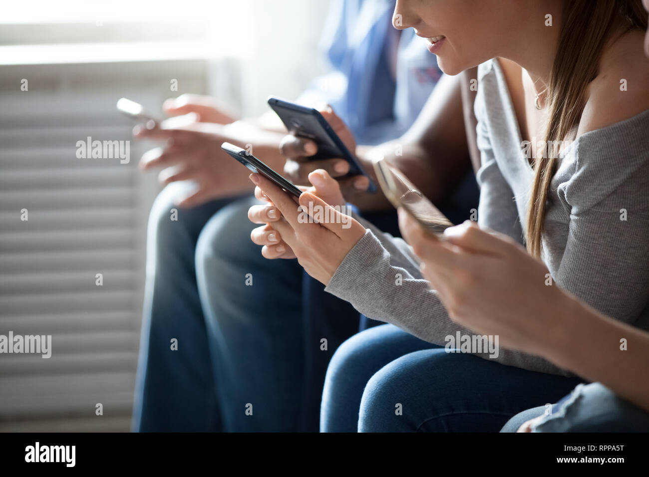 Close up people sitting in row, smiling young woman using phone Stock Photo