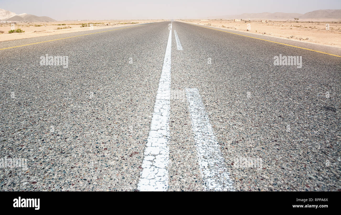 Asphalt road straight in the desert in the south of Oman Stock Photo