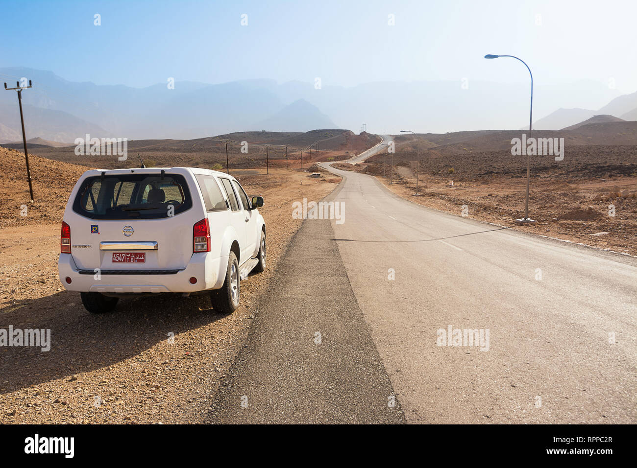 Qurayyat, Oman - November 4, 2018: Asphalt road in the Omani rocky desert and 4x4 car in a sunny day Stock Photo