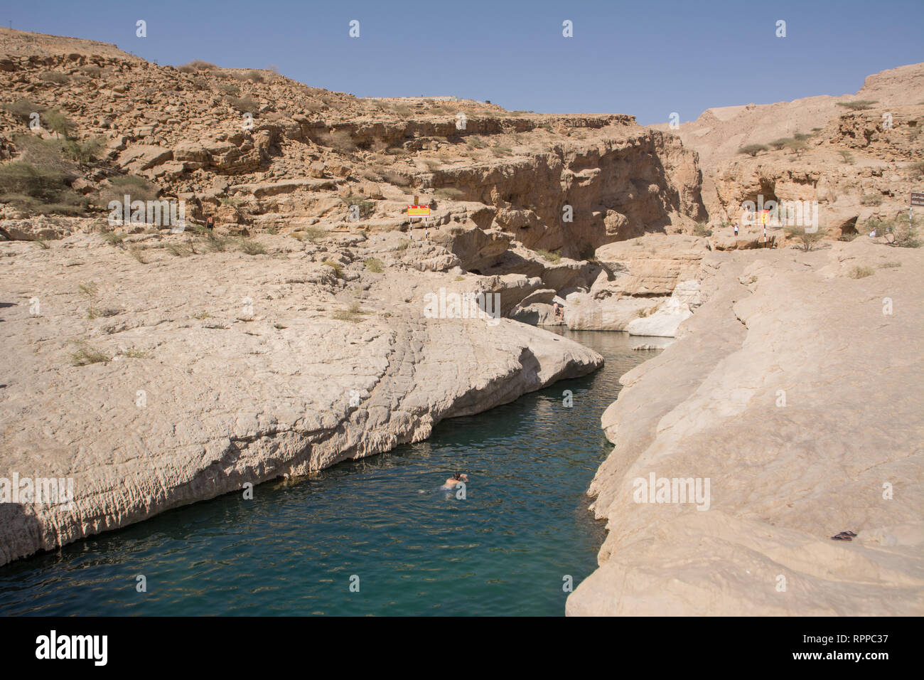Wadi Bani Khalid, Oman - November 5, 2018: Splitting into the rock with water at Wadi Bani Khalid (Oman) and bathing tourist Stock Photo
