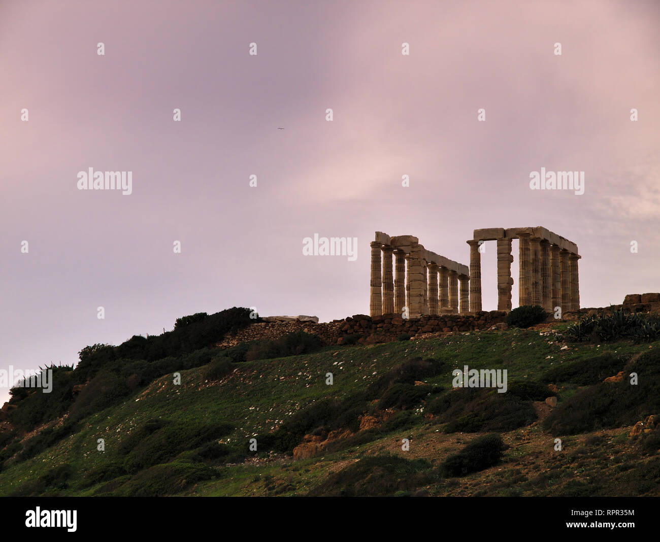 Sunset  at  ancient ruins of Poseidon temple under sky with clouds at winter time  in Sounio, Greece Stock Photo
