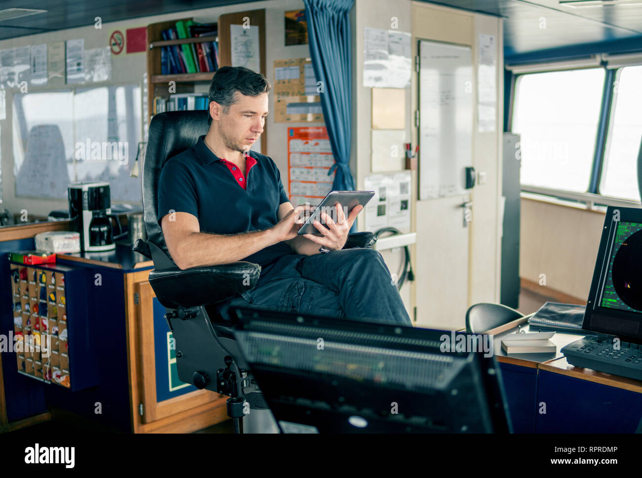 chief officer on navigation bridge watching digital tablet Stock Photo ...