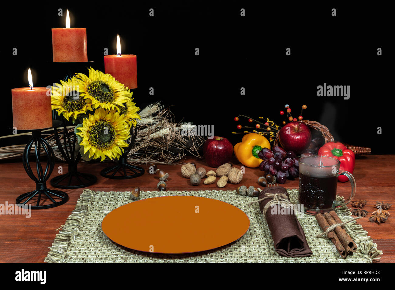 Thanksgiving setting for one with candle light, fruit, vegetables, hot tea, and sunflowers with cinnamon sticks and anise. Stock Photo