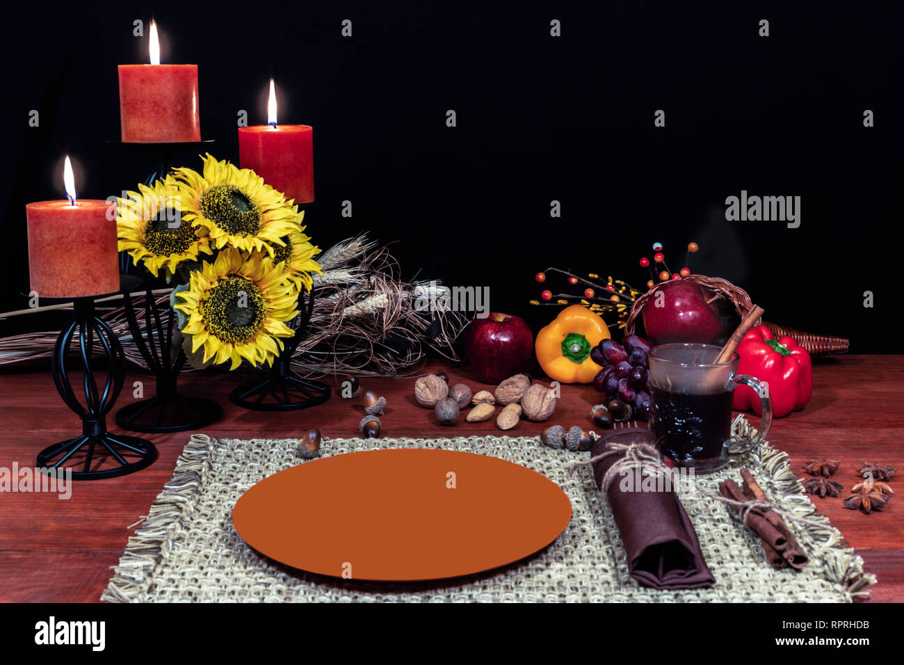Thanksgiving setting for one with candle light, fruit, vegetables, hot tea, and sunflowers with cinnamon sticks and anise. Stock Photo