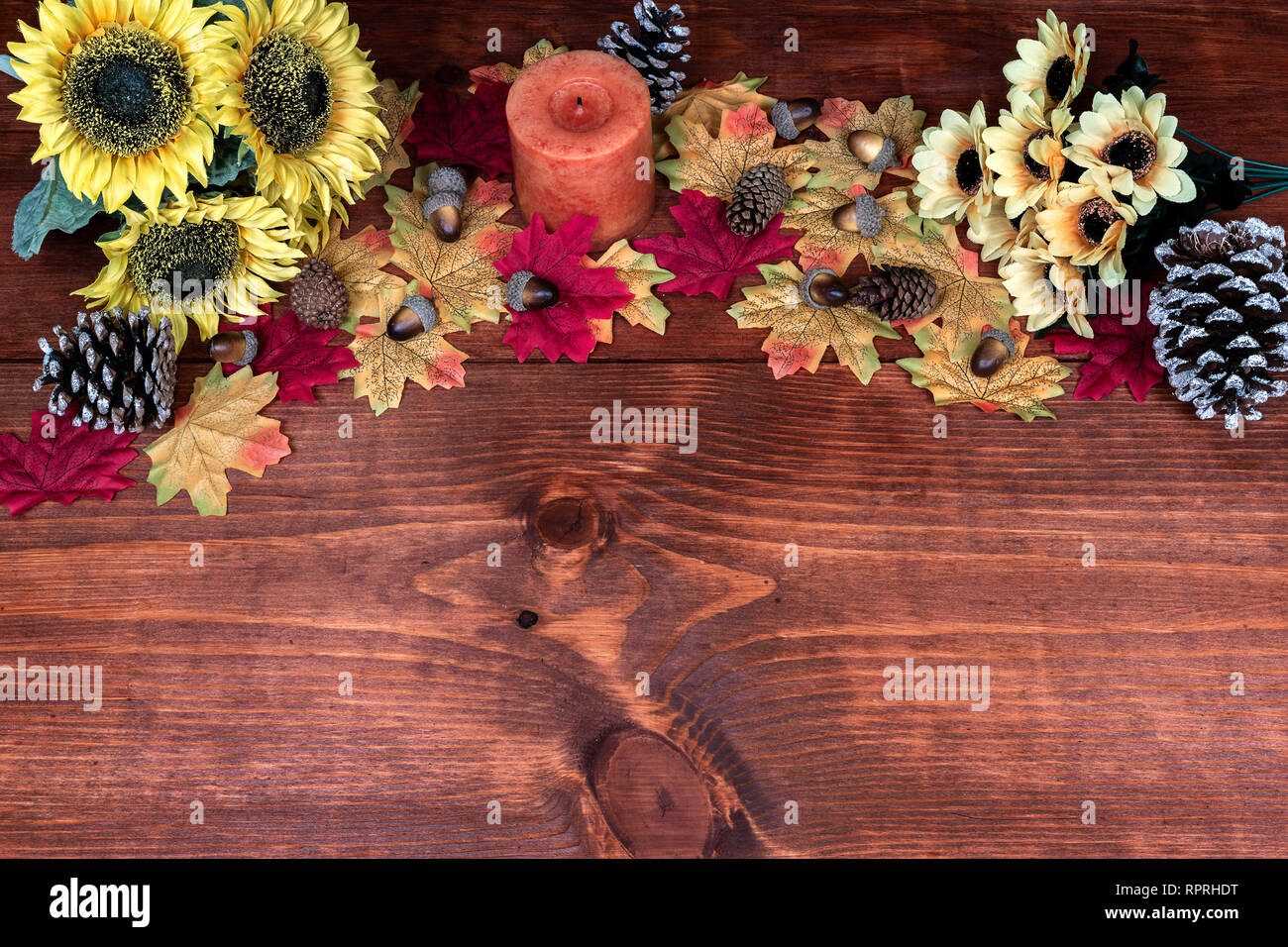 Thanksgiving decor with candle, frosted pine cones, sunflowers, acorns and maple leaves Stock Photo