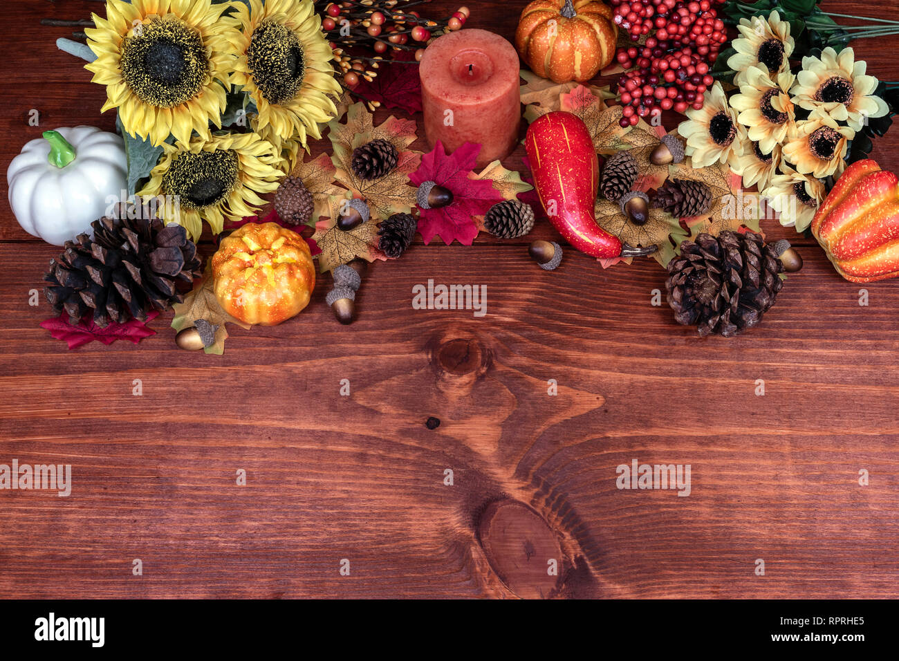 Thanksgiving decor with candle, pine cones, sunflowers, acorns, pumpkins, squash, guard, berries and maple leaves Stock Photo