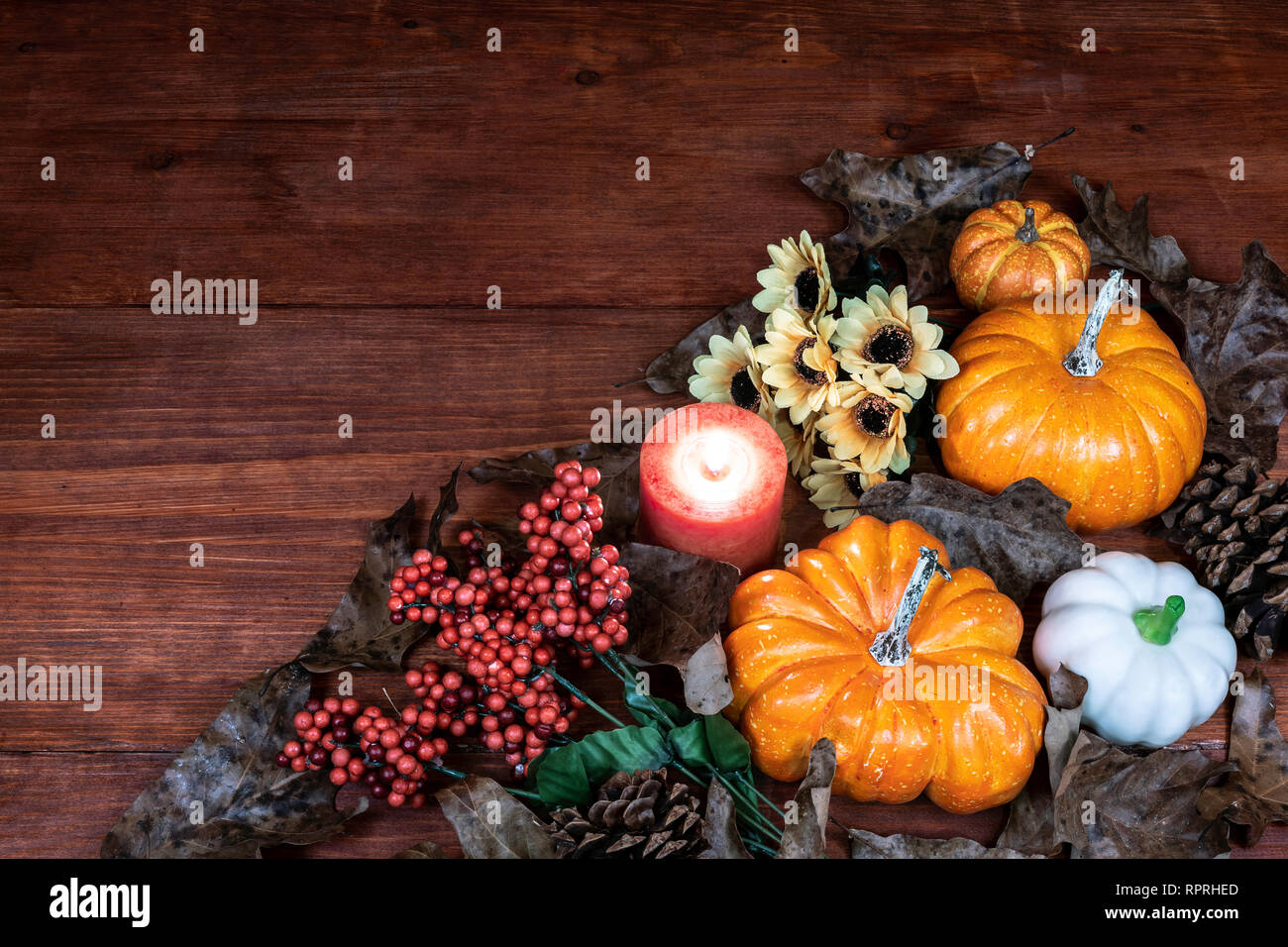Thanksgiving decor with candle, pine cones, sunflowers, acorns, pumpkins, squash, guard, berries and  leaves Stock Photo