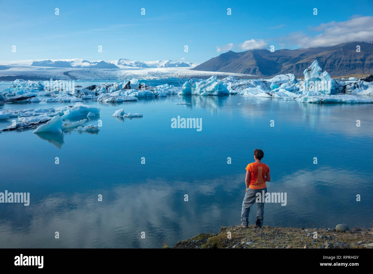 Person on the shore of Jokulsarlon glacier lagoon, beneath Vatnajokull glacier. Vatnajokull National Park, Sudhurland, south east Iceland. Stock Photo