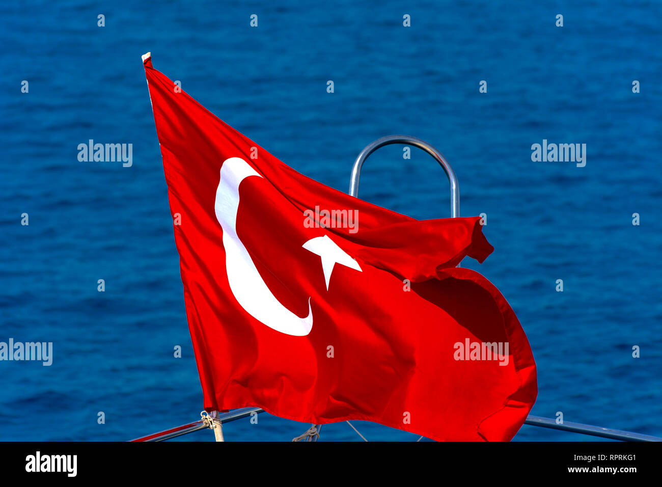 Scene flag from Turkey. The Turkish flag hovers on the bow of the yacht against the backdrop of the blue sea. The concept of vacation, boat trips and  Stock Photo