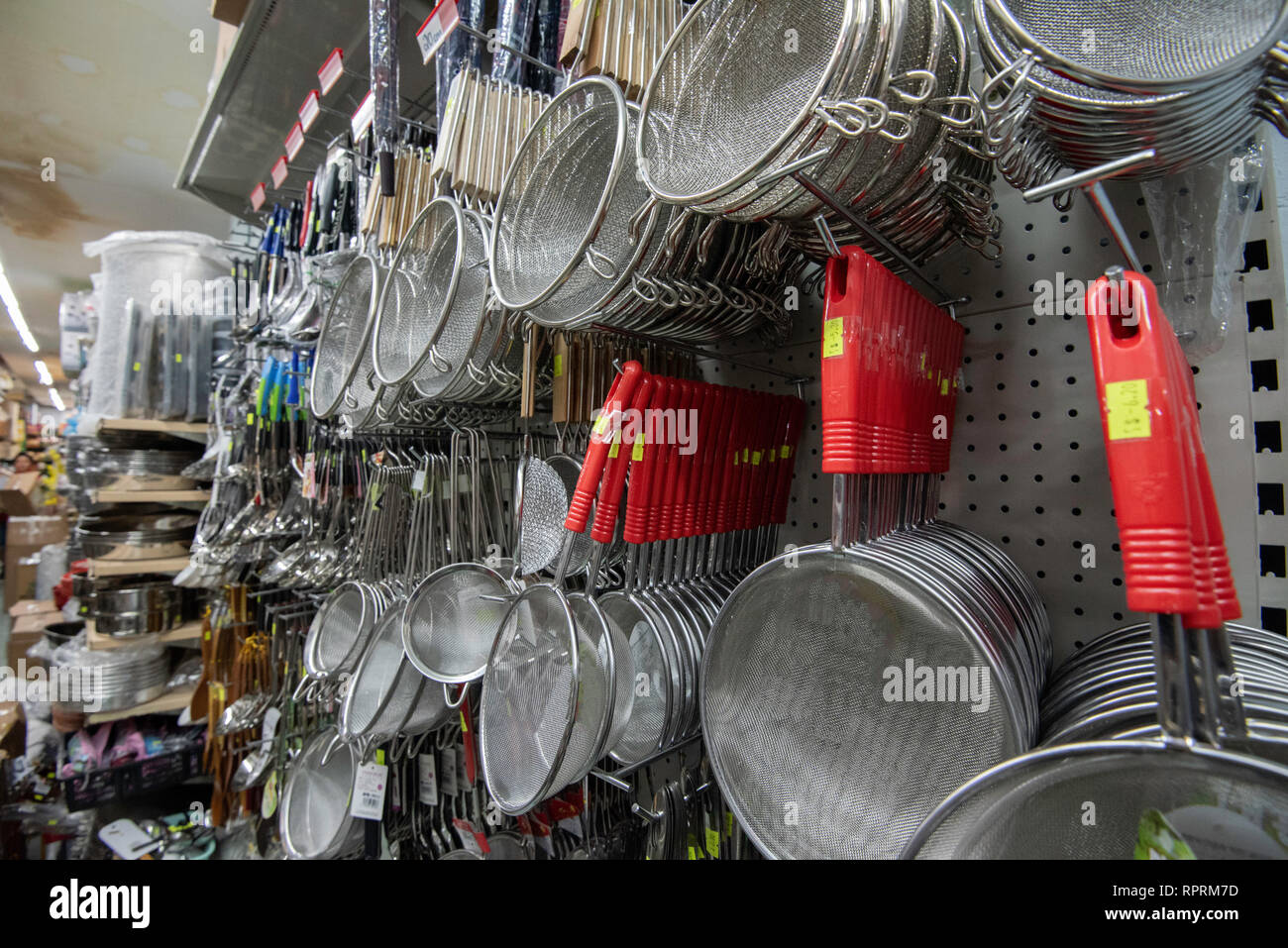 Food strainers with red plastic handles hanging for sale in an Asian supermarket or grocery store in the Sydney suburb of Cabramatta in Australia Stock Photo