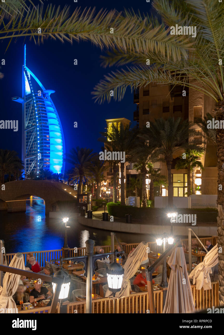 Open outdoor dining area of cafe in Dubai at night with the view of Burj Al  Arab building blue illumination in background Stock Photo - Alamy, image size:929x1390