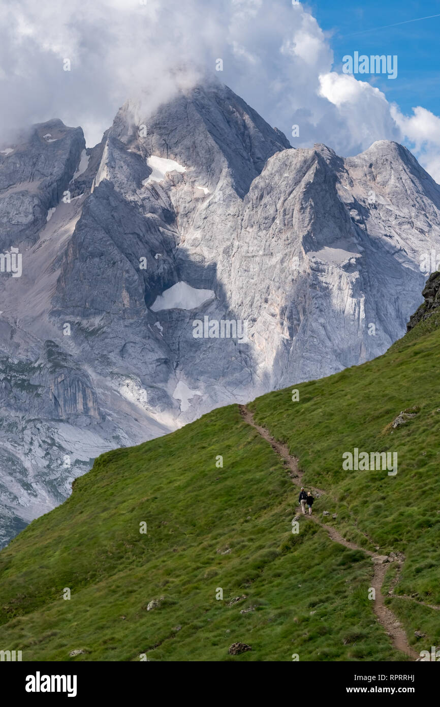 Hikers making their way through the Italian Dolomites with mighty Marmoleda mountain in the background Stock Photo