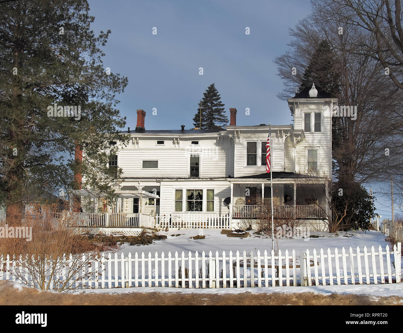 Old fashoined home with white picket fence in winter Stock Photo