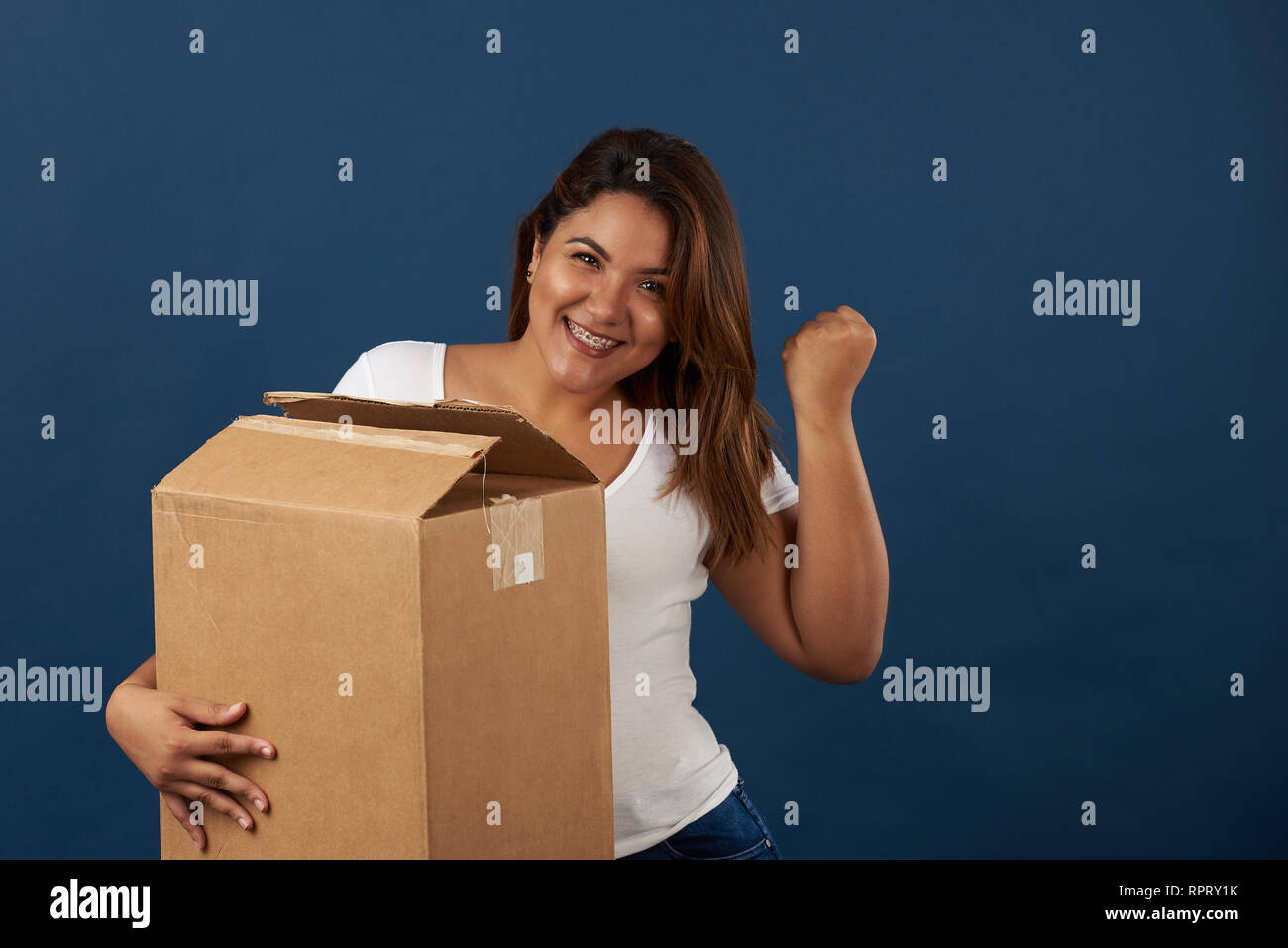 Smiling girl with package holding in hand isolated on blue studio background Stock Photo