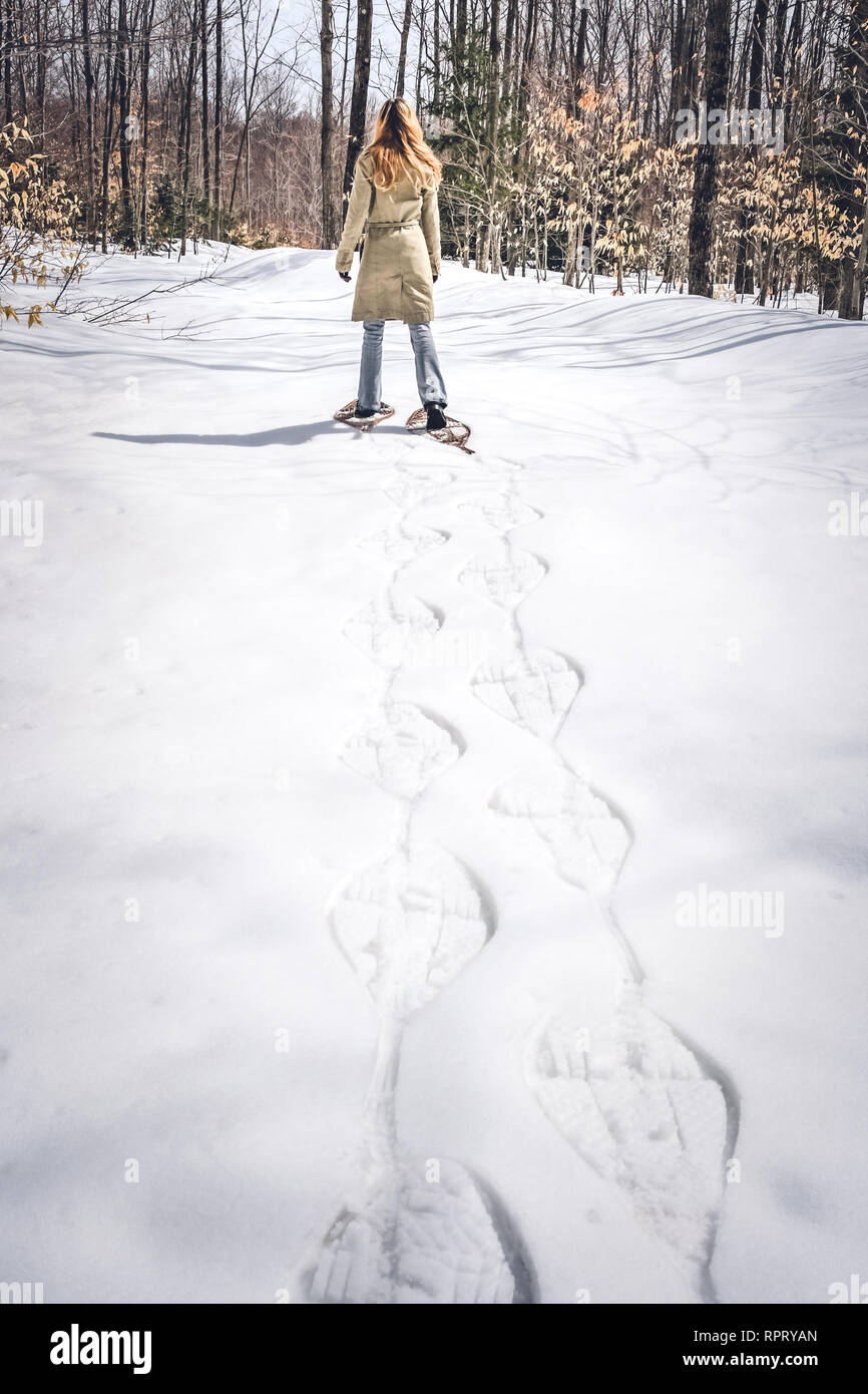 Young woman in snow shoes walking in winter forest. Rural Quebec, Canada. Stock Photo