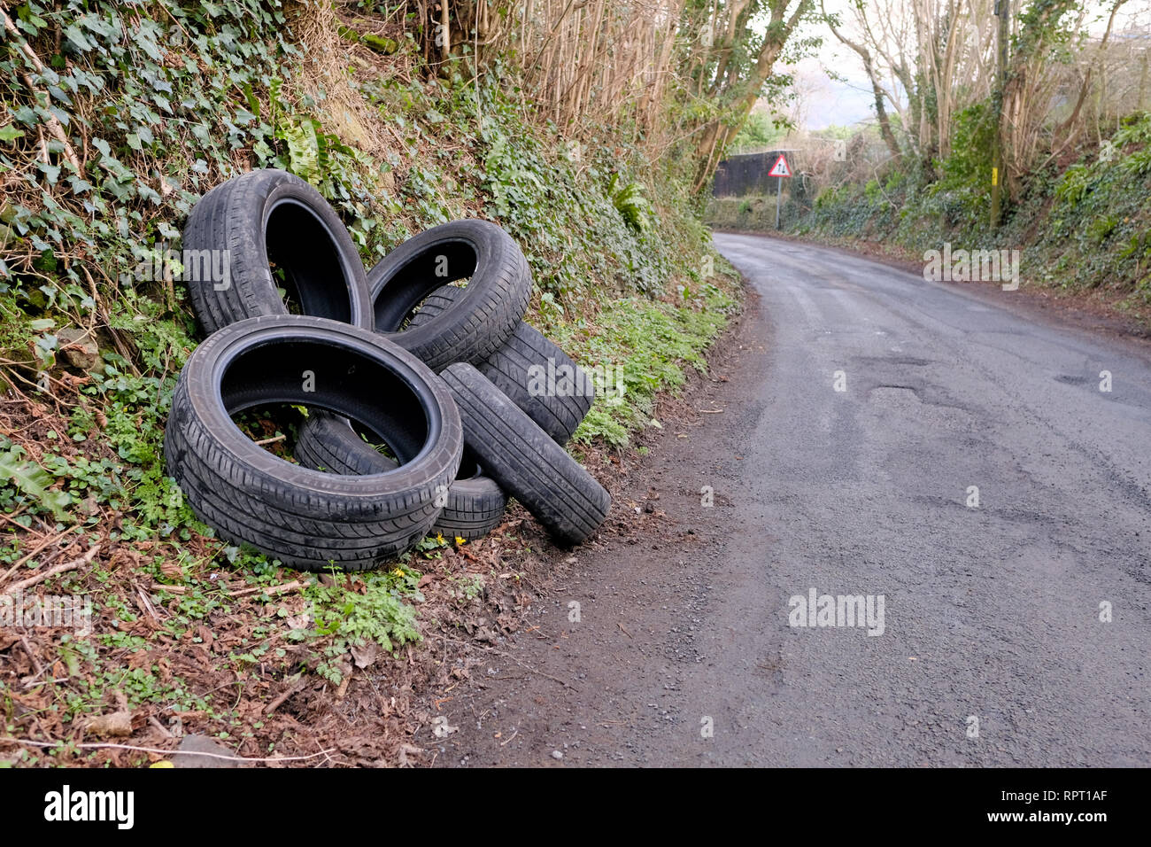 A pile of discarded, car tyres, illegally fly tipped on a country road. this fly tipping has a big impact on environmental damage in the countryside Stock Photo