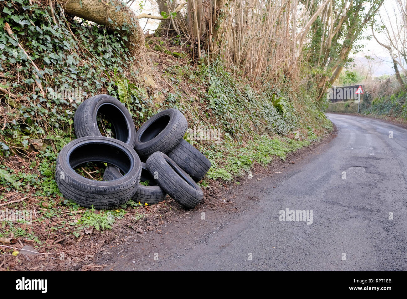 A pile of discarded, car tyres, illegally fly tipped on a country road. this fly tipping has a big impact on environmental damage in the countryside Stock Photo