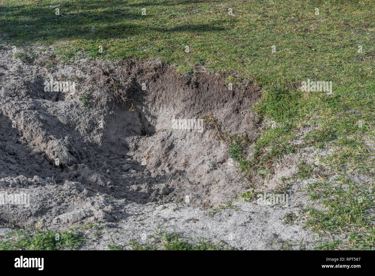 Deep hole in sandy ground. Metaphor for 'Digging a hole for Yourself
