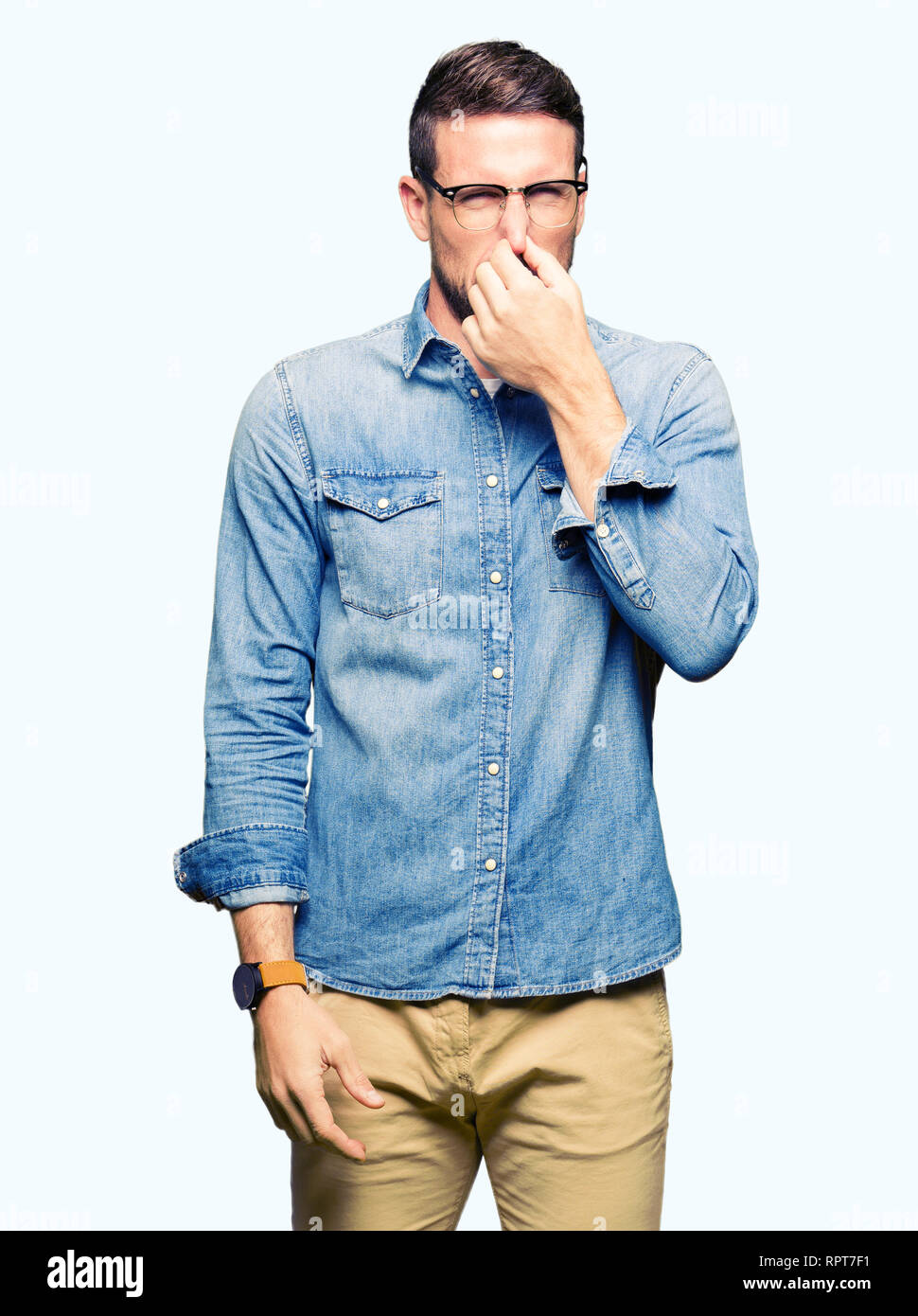 Handsome man wearing glasses smelling something stinky and disgusting