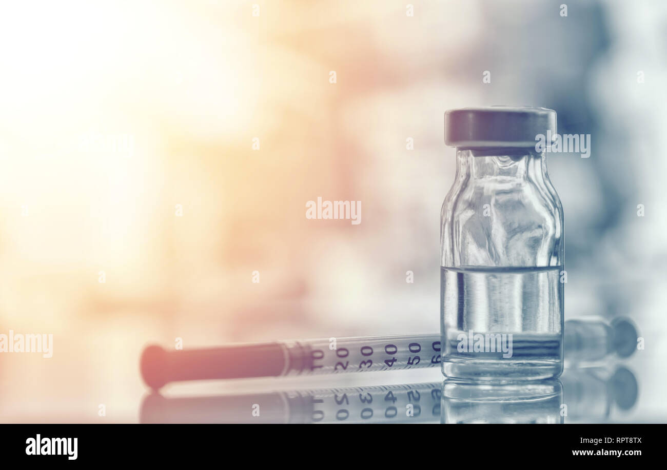Closeup of medicine vial or flu, measles vaccine bottle with syringe and needle for immunization on vintage medical background, medicine and drug conc Stock Photo