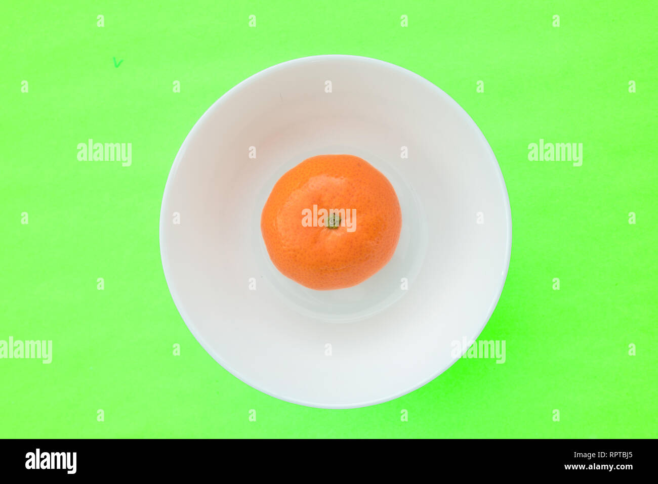 One mandarin orange in a white bowl looks like an egg with the egg yolk, creative photo Stock Photo