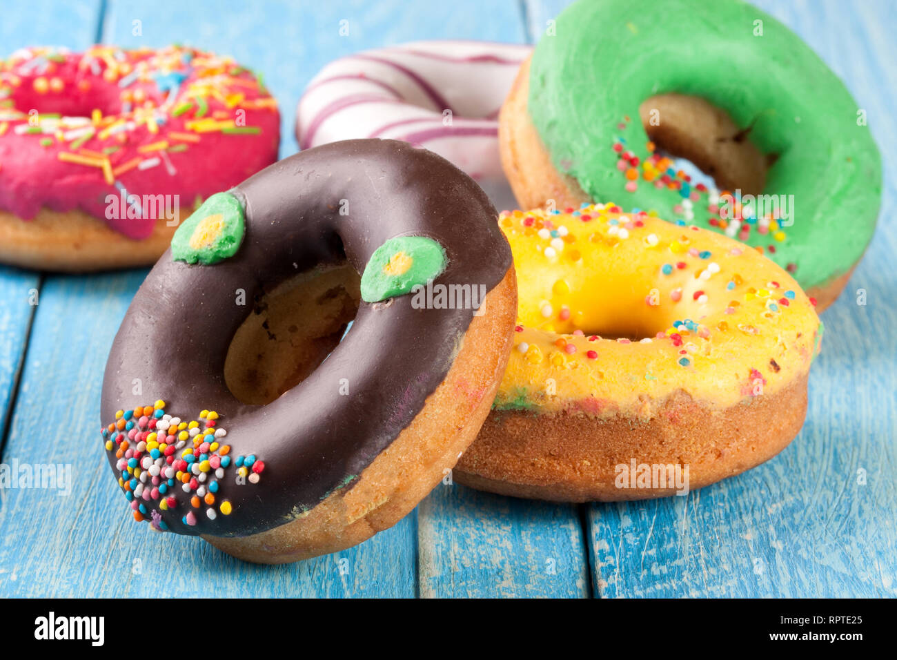 pile of glazed donuts on a blue wooden background Stock Photo - Alamy