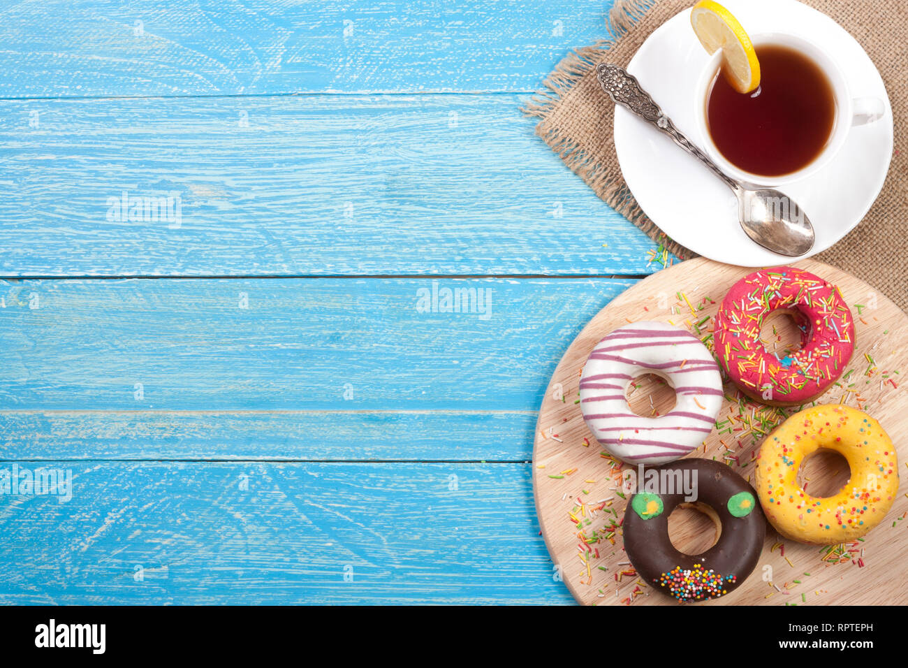 glazed donuts with a cup of tea on a blue wooden background with copy ...