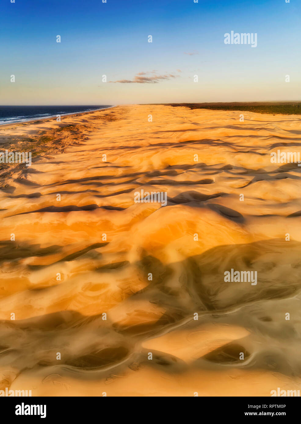 Sun lit sand dunes on Stockton beach of Australia in vertical aerial panorama from top down view to land surface up to distaint horizon and Newcastle. Stock Photo