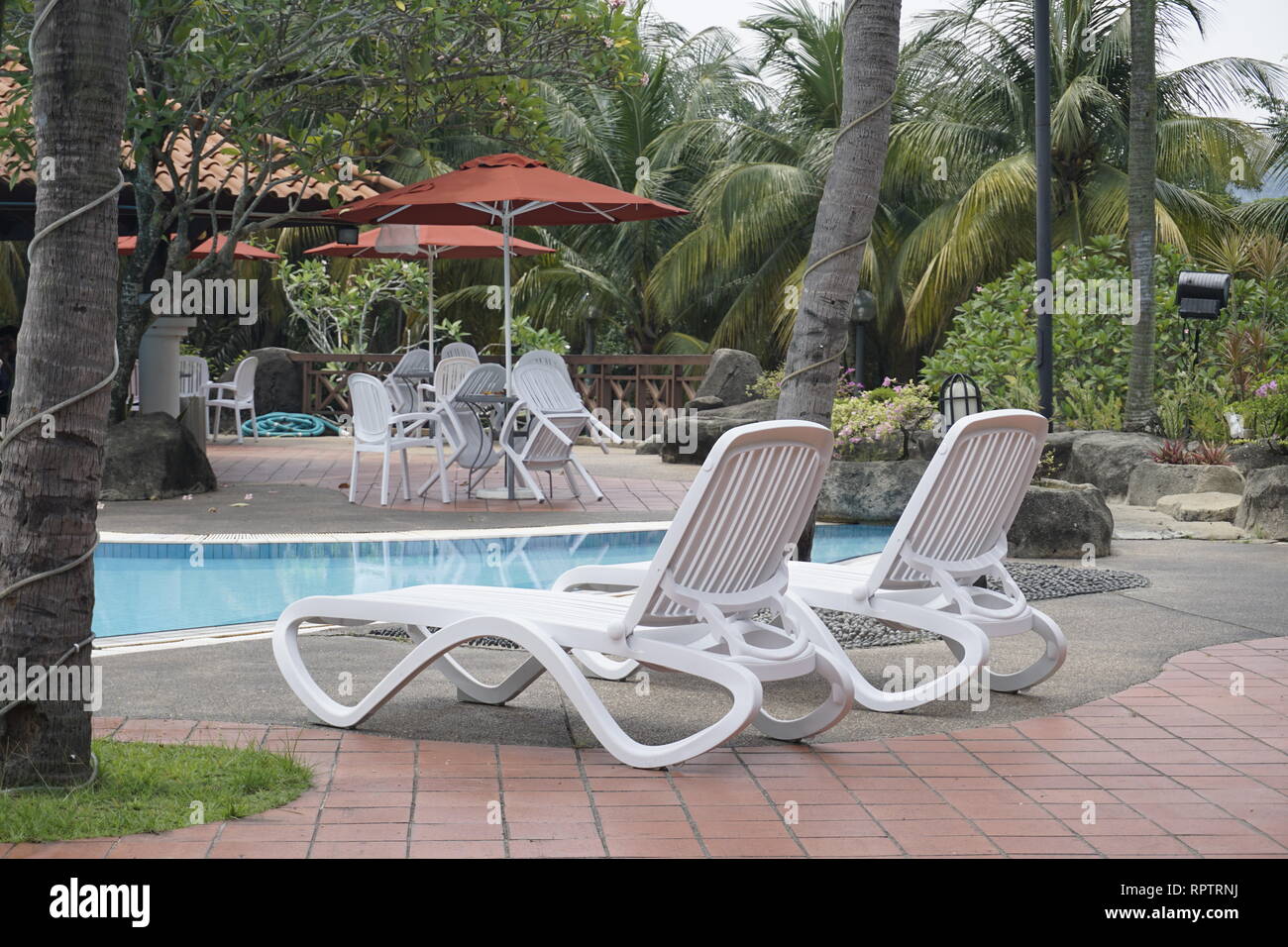 white lounge chairs at a swimming pool Stock Photo