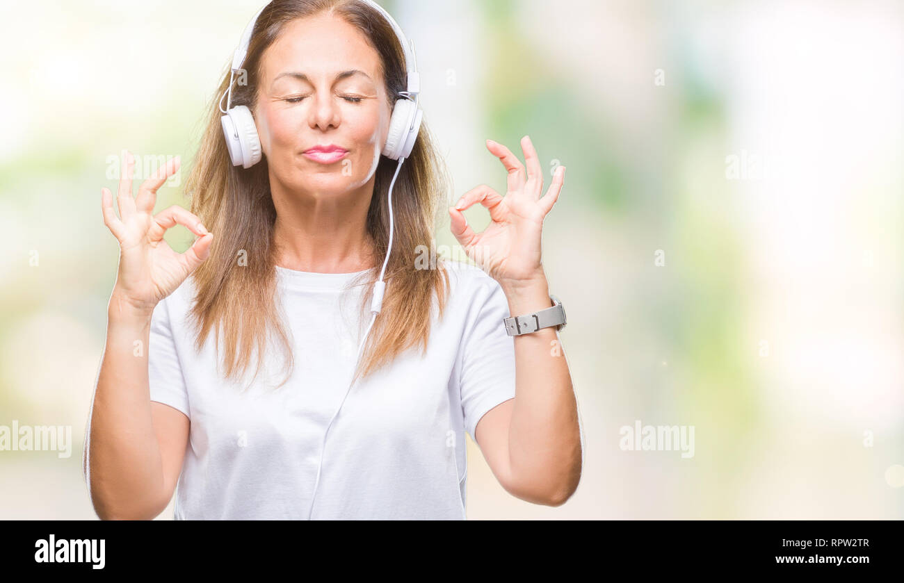 Middle age hispanic woman listening to music wearing headphones over ...